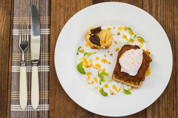 Dish with meat steak on toast, potato chips  melted cheese and poached egg  Dutch sauce. Wooden background. Top view. Close-up