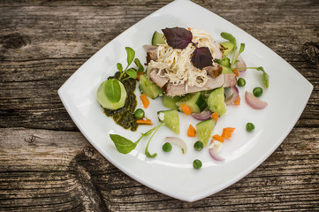 Salad with chopped baked meat, melted cheese, cucumber, carrot and pea puree. Wooden background. Close-up