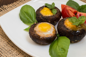 Stuffed champignon quail eggs with basil and tomatoes. Wooden background. Close-up