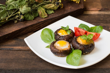Stuffed champignon quail eggs with basil and tomatoes. Wooden background. Close-up