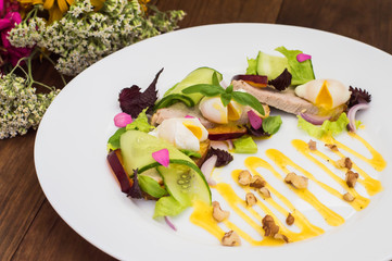 Salad of stewed meat, green, perepilinyh poached eggs, cucumbers, basil, plum and Dutch sauce with walnuts. Wooden background. Top view. Close-up
