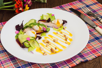 Salad of stewed meat, green, perepilinyh poached eggs, cucumbers, basil, plum and Dutch sauce with walnuts. Wooden background. Top view. Close-up