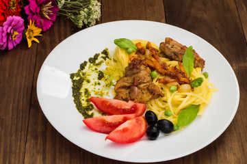 Tagliolini with meat in tomato sauce, olives and   spinach. Wooden background. Close-up. Top view