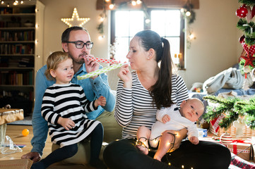 Parents with children at Christmas tree blowing party whistles