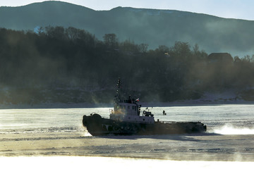 marine tug floats on the sea freezes along the ice floe with the fishermen