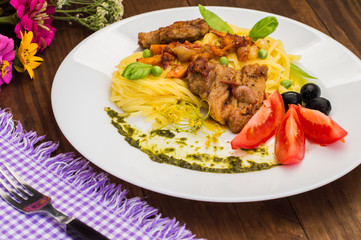 Tagliolini with meat in tomato sauce, olives and   spinach. Wooden background. Close-up. Top view