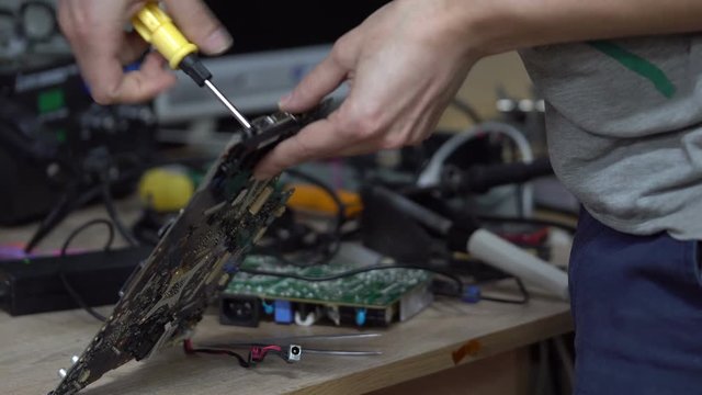 Technician holding the motherboard in the hands. Maintenance in the workshop.