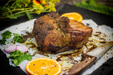 Baked pork ribs with sauce and basil on a black table. Top view. Close-up. Selective focus