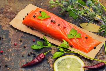 Fresh trout steak with spices, herbs and lemon. Old background. Top view. Close-up