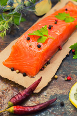 Fresh trout steak with spices, herbs and lemon. Old background. Top view. Close-up