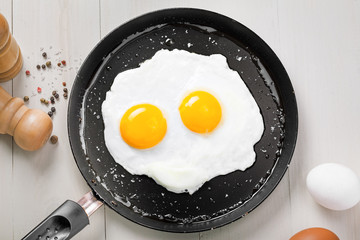 Fried eggs for delicious healthy easy breakfast on a table. Fresh homemade meal on a frying pan. Traditional breakfast food. International cuisine food.  Top view.