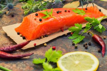 Fresh trout steak with spices, herbs and lemon. Old background. Top view. Close-up