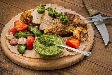 Meat with vegetables, grilled and served  Italian Salsa Verde sauce. Wooden rustic table. Close-up
