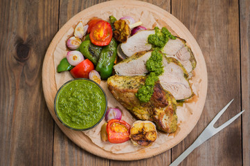 Meat with vegetables, grilled and served  Italian Salsa Verde sauce. Wooden rustic table. Close-up