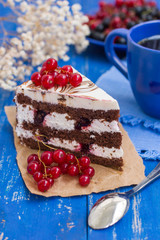 Biscuit cream cake with cherries and red currants. Wooden background. Close-up