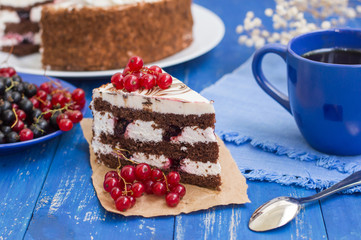 Biscuit cream cake with cherries and red currants. Wooden background. Close-up