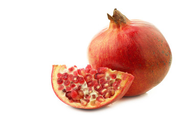 one whole pomegranate(Punica granatum)and a cut piece on a white background