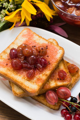 Toast with gooseberry jam. Wooden background  flowers. Top view. Close-up