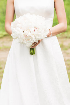 Bride. Bridal bouquet. Bride holding a bouquet. Wedding photo concept. Summer wedding.Sensual Wedding Photo. White peonies