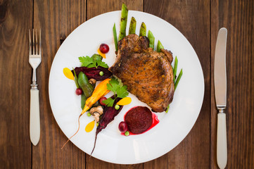 Fried Grilled pork steak on the bone with vegetables, mashed beetroot and berry sauce. Wooden background. Top view. Close-up
