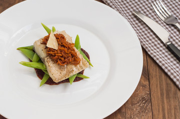 Cooked fish with steamed asparagus, vegetable ragout, tomato sauce and potato chips. Wooden background. Top view. Close-up
