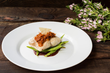 Cooked fish with steamed asparagus, vegetable ragout, tomato sauce and potato chips. Wooden background. Top view. Close-up