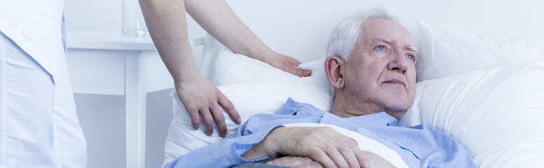 Older sad man in hospital bed