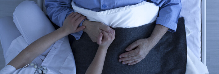 Nurse holding older man's hand