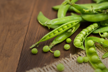 Pea pods on sacking. Wooden background. Top view. Close-up