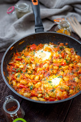 Homemade Traditional Israeli Breakfast Shakshuka with Eggs, Tomato Sauce and Herbs, Vertical View