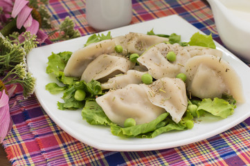 Dumplings with minced chicken on a plate  fresh herbs and peas. Wooden background. Close-up
