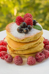 Pancakes with raspberries, currants, sugar and mint. Against the background of greenery. Close-up