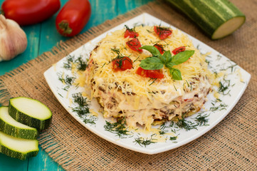 The cake of zucchini with cheese, tomato and basil. Wooden background. Close-up