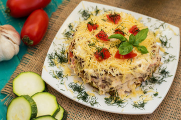The cake of zucchini with cheese, tomato and basil. Wooden background. Close-up