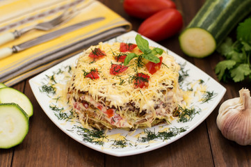The cake of zucchini with cheese, tomato and basil. Wooden background. Close-up