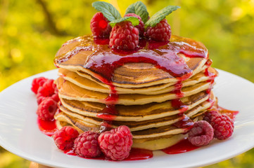 Pancakes with raspberry jam and fresh berries. Wooden background. Close-up