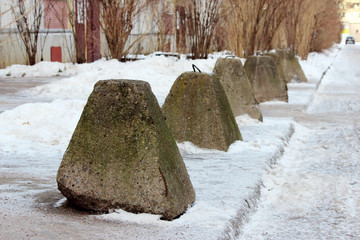 antiterrorist pyramidal concrete pedestals near the house beside the road against the entry of...