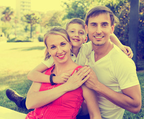 Portrait of cheerful family with boy in school age happily huggi