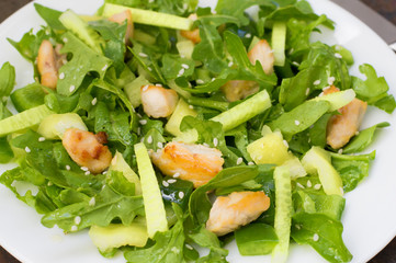 Arugula salad, paprika, cucumber, fried chicken and sesame seeds. Wooden background. Close-up