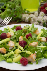 Salad with raspberries, arugula, cucumber, paprika, roasted chicken and sesame. Wooden background. Close-up