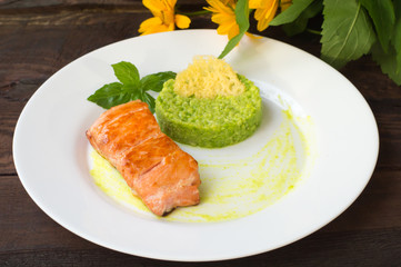 Grilled salmon steak with pea puree, cheese crisps and basil on a plate  the sauce. Wooden rustic background. Top view. Close-up