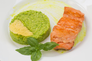 Grilled salmon steak with pea puree, cheese crisps and basil on a plate  the sauce. Wooden rustic background. Top view. Close-up