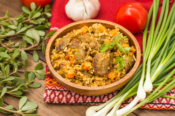 Uzbek pilaf - a dish consisting of rice and meat. At the traditional wooden background. Close-up