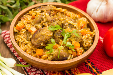 Uzbek pilaf - a dish consisting of rice and meat. At the traditional wooden background. Close-up