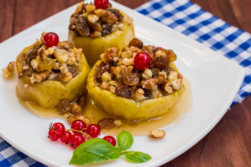 Baked apples with raisins, walnuts and honey for dessert. Wooden rustic background. Close-up