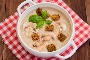 Mushroom cream soup with croutons of rye bread and basil. Wooden rustic background. Top view. Close-up.