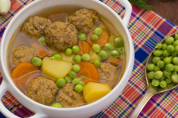 Soup with meatballs, carrots and peas. Wooden rustic background. Top view. Close-up