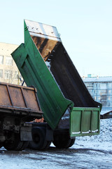 Green truck with a raised body in the parking lot next to the building of the house