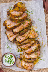 Pork steak cooked on the grill, marinated in herbs and rosemary, served  a table with tzatziki sauce. Background paper for baking. Top view. Close-up