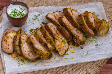 Pork steak cooked on the grill, marinated in herbs and rosemary, served  a table with tzatziki sauce. Background paper for baking. Top view. Close-up